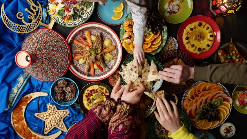 Ramadan food. Celebrating Eid al-Fitr. Family and friends eat traditional Middle Eastern holiday food together at the table | Shutterstock HD Video #1100521317