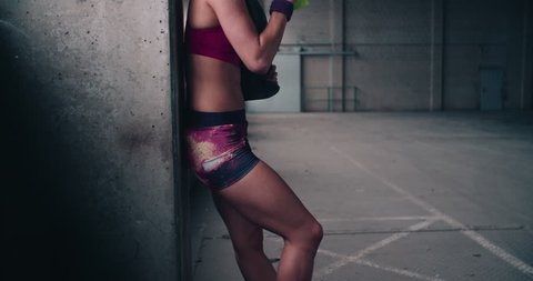 Cropped image of a woman with a fit body holding a green water bottle, jump rope and wearing colourful pink and purple sporswear: film stockowy