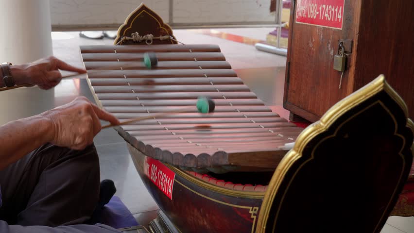 Male hands quickly playing a tune on wooden ranat thai xylophone using mallets, Thailand