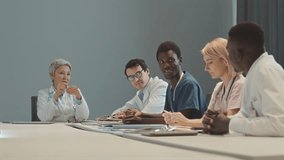 Waist up shot of diverse medical team having meeting with mid adult Asian female chief doctor sitting at head of table in modern conference room - Powered by Shutterstock - Get 15% off with code: PIKWIZARD15