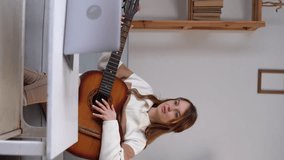 Female vlogger or teacher playing guitar and recording tutorial, young woman blogger teaching play songs and instrumental music online lessons. Online training, online classes.