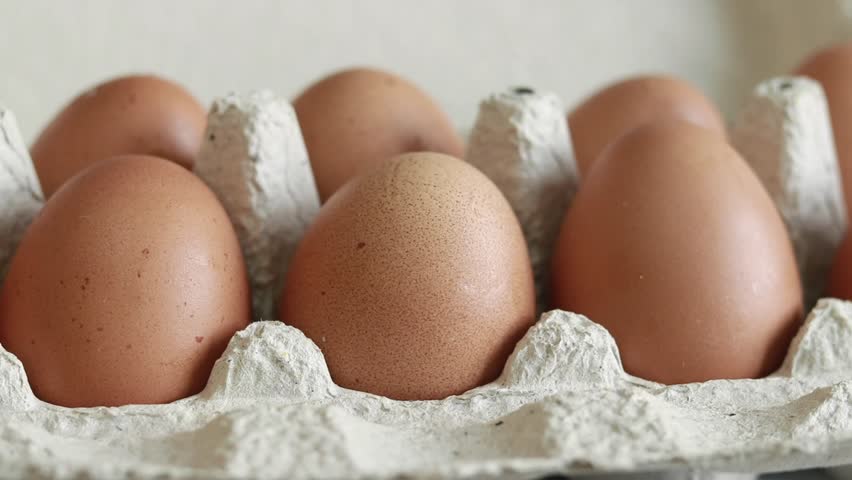 Chicken eggs in a cardboard box. Fresh raw eggs in a paper egg container. A woman's hand takes an egg from the package Royalty-Free Stock Footage #1100538689