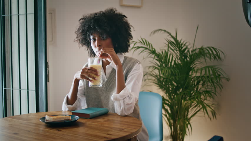 Confident attractive businesswoman tasting drink sitting cozy cafe with book close up. Thoughtful african american woman enjoy tasty cocktail relaxing alone in restaurant. Rest leisure hobby concept. | Shutterstock HD Video #1100538991