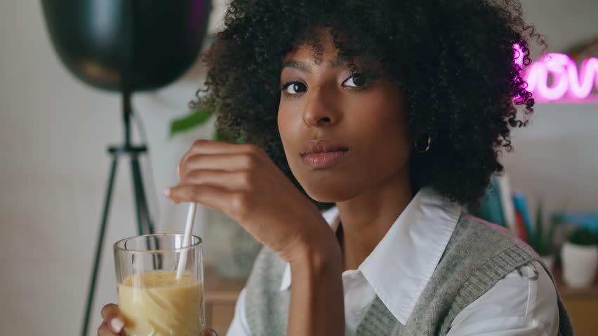 Dreamy beautiful woman drinking cocktail in cozy cafe close up. Curly pensive african american girl sitting in restaurant alone tasting delicious drink with straw. Pretty relaxed lady enjoy beverage Royalty-Free Stock Footage #1100539033