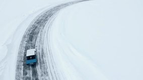 Aerial view of a frozen snow and ice covered lake with bending track. Clip. Drifting car on a winter day.