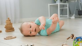 Baby rolling. Cute little baby rolling over on floor at home among toys. Infant leisure at home. Infant development skills.
