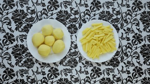 Raw french fries. Raw potatoes cut into strips, prepared for french fries, isolated on a white plate. Peeled potatoes. Cooking, raw vegetables : vidéo de stock