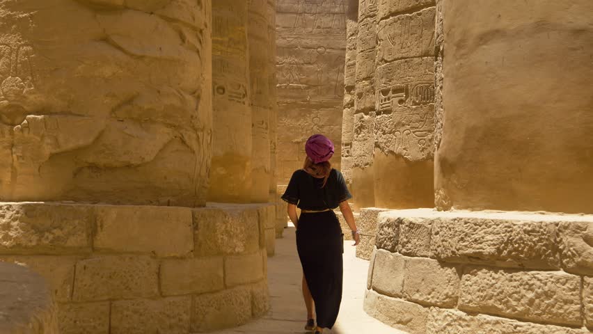 Egypt - circa 2022 - a tourist walks among the columns of egypt's karnak temple complex. Royalty-Free Stock Footage #1100550091