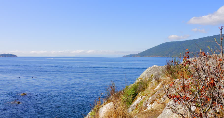 Establishing shot of ocean beach with rocks and pebbles in slow motion at summer day in Vancouver, Canada, North America. Day time on September 2022. Still camera. ProRes 422 HQ.