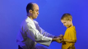 On a blue background, dad and son are training hand strikes on the palms