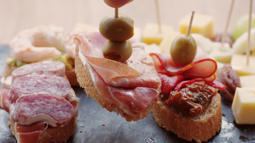 Italian or Spanish restaurant with traditional tapas food, Spanish cuisine, delicious tapas and cheese plate, bruschetta with cheese, olives dry tomatoes and tasty sandwich bar appetizer, buffet Royalty-Free Stock Footage #1100563983