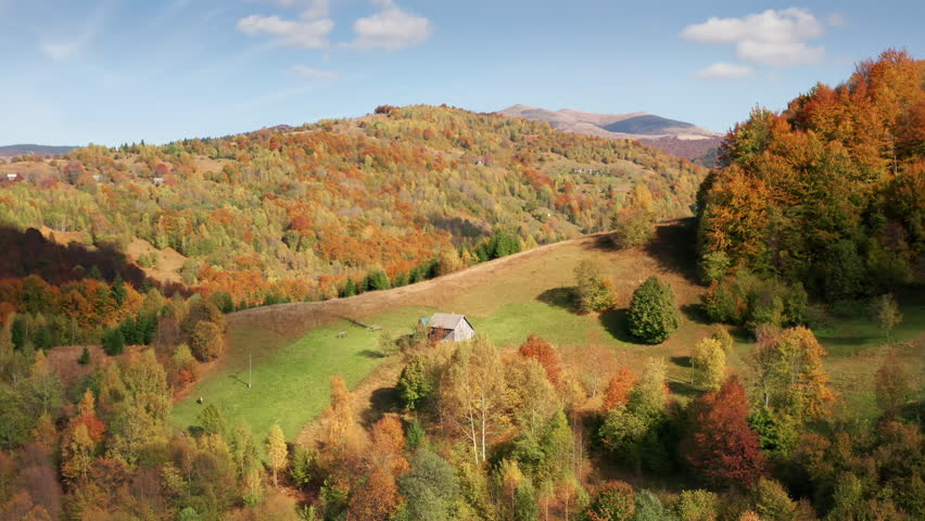 Aerial view of remote countryside area with lush greenery around. Astonishing travel getaway among brilliant fall foliage across the steep slopes. High quality 4k footage