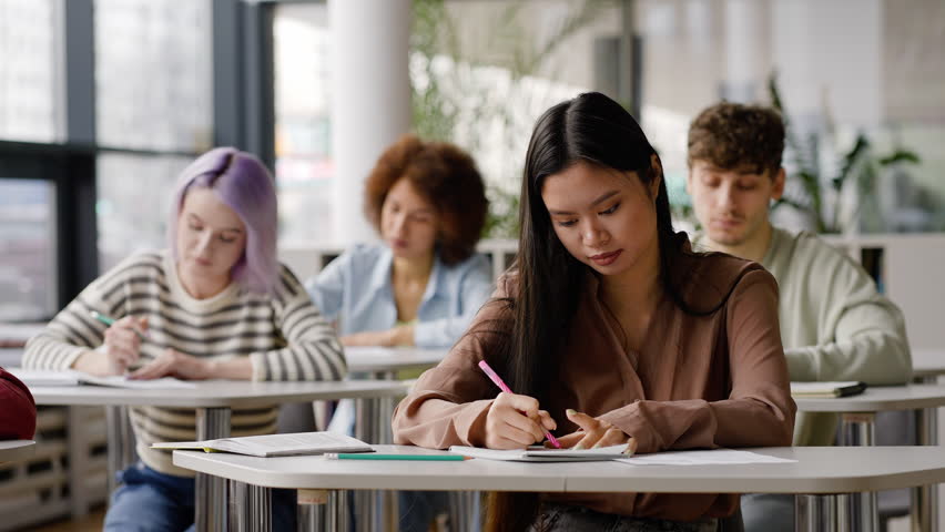 Diverse teenage students writing objective test in class, or a lecture under professor's dictation. Open to new knowledges in the new semester of academic year Royalty-Free Stock Footage #1100568067