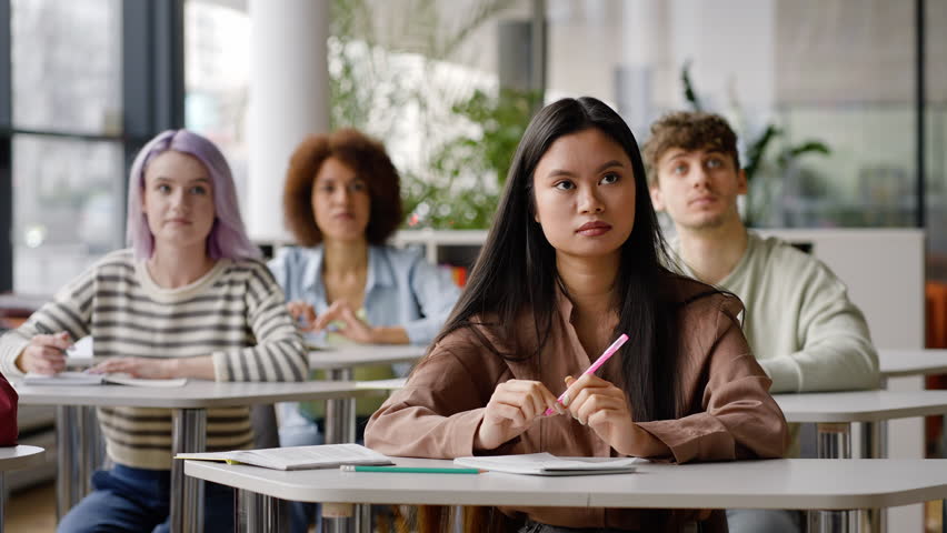 Young teenage diverse students taking notes during a lecture in the library campus of high school institution. Open to new knowledges in the new semester of academic year Royalty-Free Stock Footage #1100568111