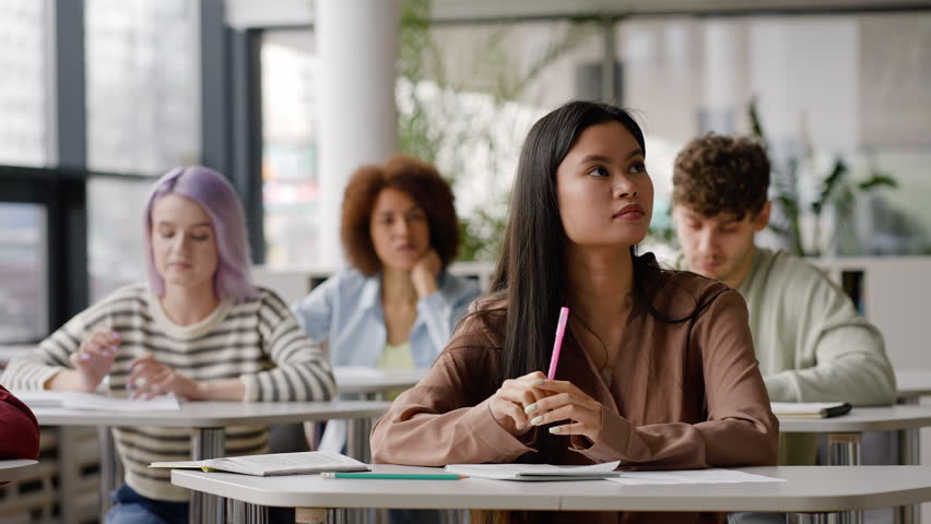 Diverse teenage students writing lecture under professor's dictation, smiling a cheerful toothy smile, enjoying university learning process. Open to new knowledges in the new semester of academic year Royalty-Free Stock Footage #1100568153