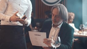 In the restaurant waiter takes the order of mature man. Senior businessman with menu order lunch in cafe. Mature elegant man order meal in restaurant. Realtime - Powered by Shutterstock - Get 15% off with code: PIKWIZARD15