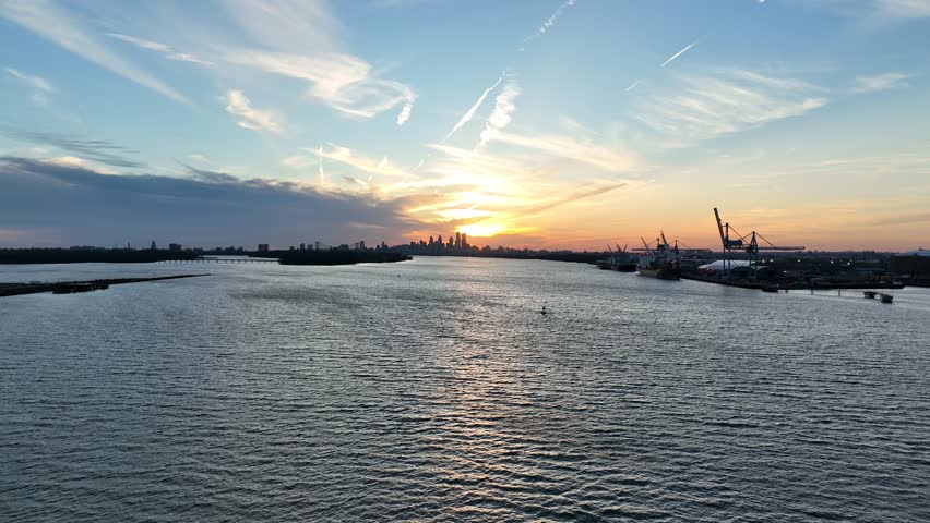 Aerial View Flying over Delaware River Towards Sunset over City of Philadelphia