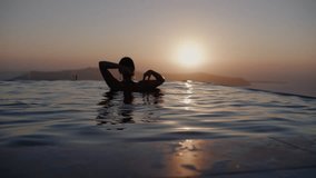 A woman dancing in infinity pool watching sunset over sea - Slow motion, Santorini, Greece - Powered by Shutterstock - Get 15% off with code: PIKWIZARD15