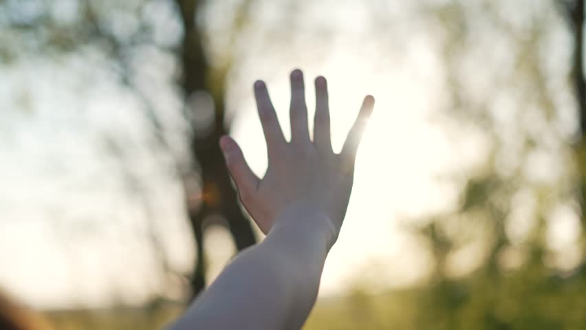 Happy girl stretches her hands to sun. Children palm in rays of sun at sunset.Young woman raising her hands praying at sunset or sunrise.Freedom in nature and spirituality concept.Fingertips touch sun Royalty-Free Stock Footage #1100574555