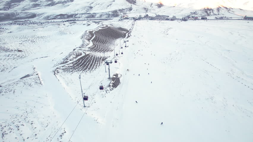 Gondola type cable car and skiers on snow covered slope of ski resort. Landscape with snowy ski piste and skiers. Aerial view. Erciyes Mount, Kayseri province, Turkey