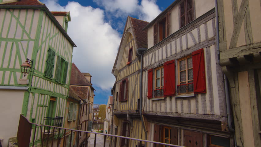Classic medieval French facades of houses and hotels in the center of the old city not far from Paris against the backdrop of a blue sky and blue clouds. Colored buildings of old houses in France