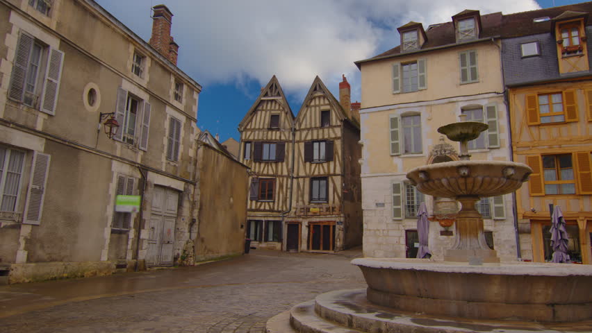 Classic medieval French facades of houses and hotels in the center of the old city not far from Paris against the backdrop of a blue sky and blue clouds. Colored buildings of old houses in France