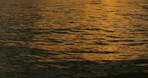 Waves and reflections at sunset. Sunlight sparkles over ocean waves. Reflection of sunlight over lake surface.