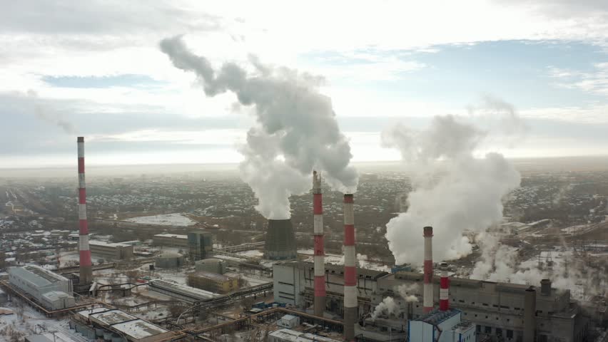 Drone flying around a thermal power plant with smoking chimneys against the backdrop of a city covered in smog and snow. B-roll 4k Royalty-Free Stock Footage #1100580757