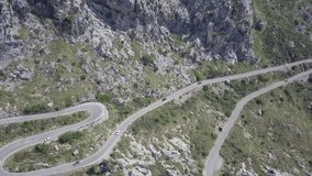 Panoramic drone view of a winding remote road with some cars driving in.