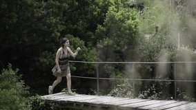 Defocusing view of a young woman walks by a wooden bridge in slow-motion