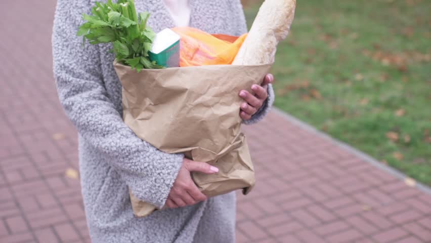 Woman carrying a paper bag with groceries | Shutterstock HD Video #1100581885