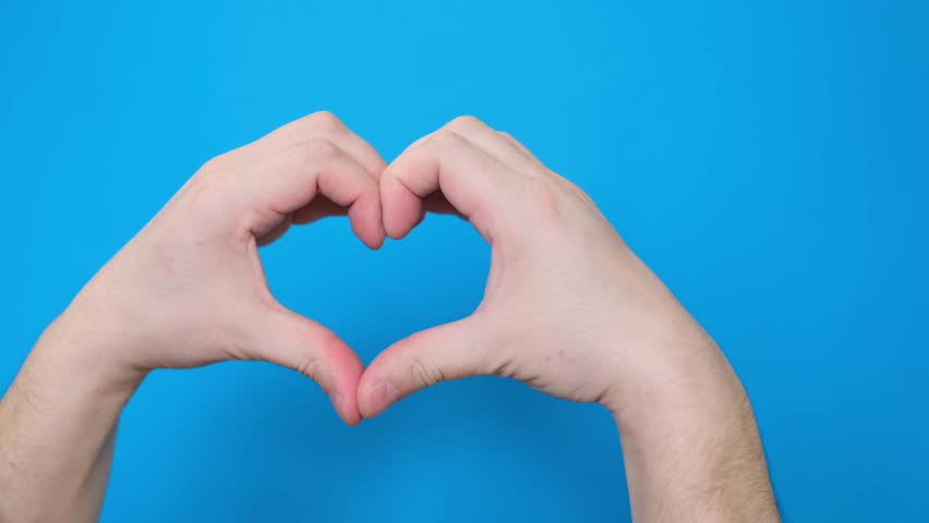 A view of a male hand making a heart-shaped gesture, isolated on a blue screen chromakey background