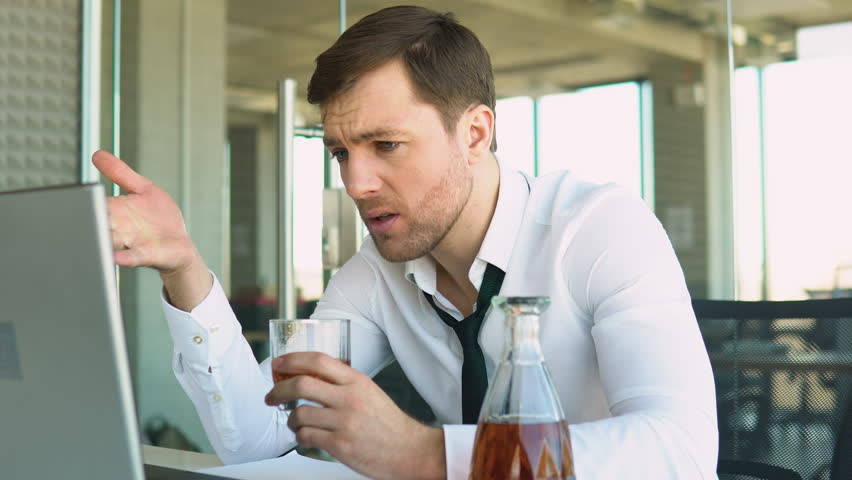 Young businessman drinking from stress at workplace | Shutterstock HD Video #1100582955