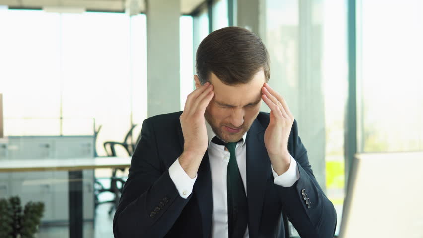 Stressed young man suffering from muscles tension, having painful head feelings due to computer overwork or sedentary working lifestyle. Tired employee overwhelmed with tasks in office | Shutterstock HD Video #1100582987