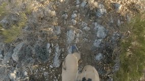 Personal view from above of legs and foots of a caucasian man running down a technical and difficult mountain path next to a edge. He wears sportswear. Video filmed in 4K 60fps usable for slow motion.