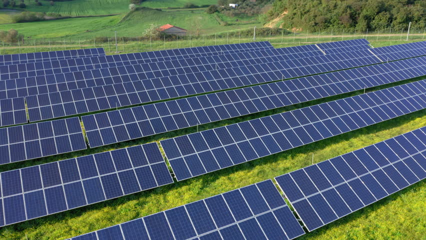 Aerial: Photovoltaic solar panels on green field during a sunny day | Shutterstock HD Video #1100588175