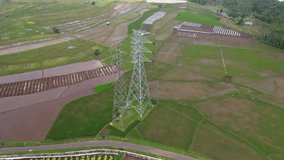 Aerial drone shot over high voltage electricity tower in the middle of rice field - Indonesia, Asia