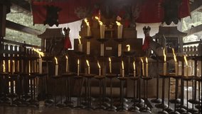 This video shows an Inari shrine with lit incense and candles blowing in the wind in slow motion.