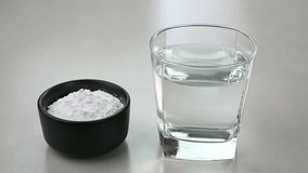 Mixing baking powder in a glass of water using spoon.