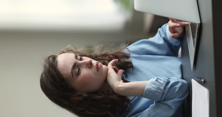 Young 25s woman sit in homeoffice working on laptop doing remote freelance tasks looks pensive or concerned, thinks of problems, search solution, busy in creative telework, brainwork or study process | Shutterstock HD Video #1100614223