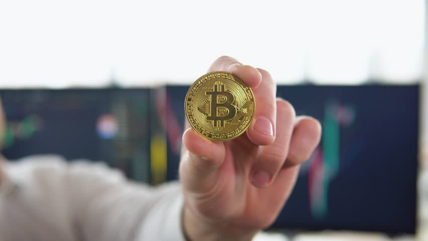 Golden Bitcoin in a man hand. Digitall symbol of a new virtual currency