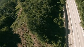 Dynamic flying with FPV racing drone along a winding road and under and above an old railway bridge following a white van in 3rd person style. Motorcycle driving in opposite direction. LuPa Creative.