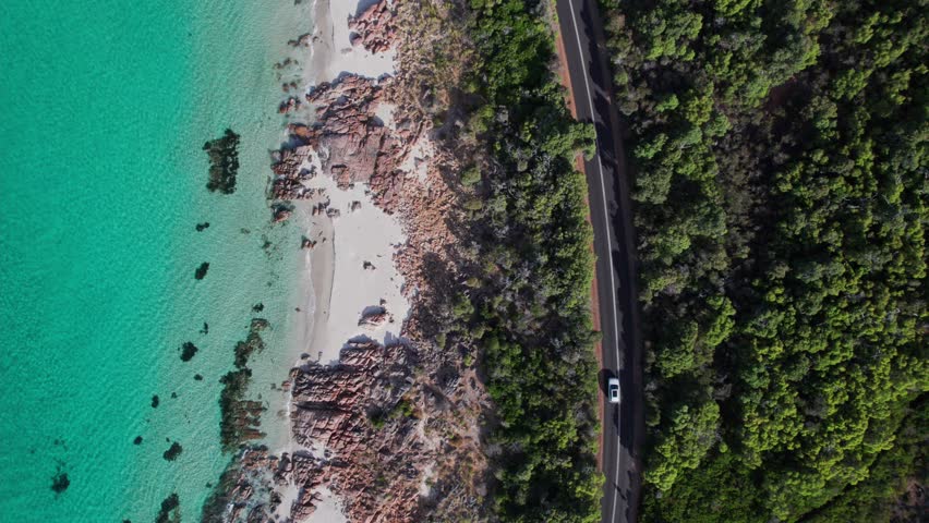 Topdown aerial of car driving next to the crystal clear waters of Eagle Bay