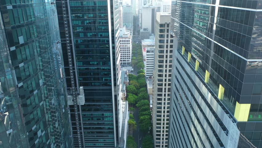 Aerial panning down shot of Brisbane skyscraper under construction with a descending external lift. Awe-inspiring aerial shot showcases modern engineering at its finest.