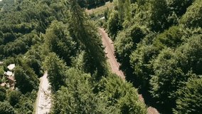 Dynamic flying with FPV racing drone through a gap in the trees low above a railway track on an old railway bridge and a winding road. LuPa Creative.