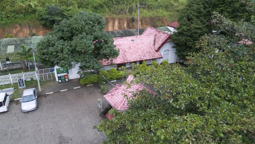 Ella town train station in Sri Lanka. Picturesque old building with a red roof. Cinematic aerial shot.