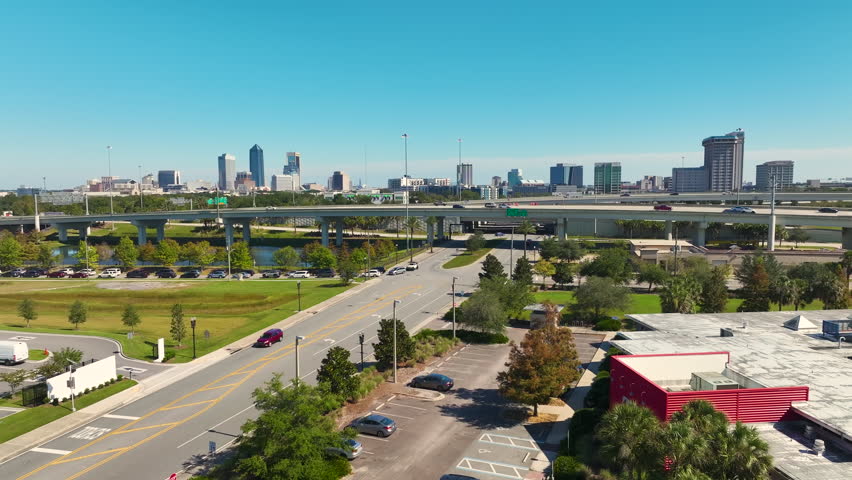 Aerial view of Jacksonville city with high office buildings and american freeway intersection with fast moving cars and trucks. USA transportation infrastructure concept
