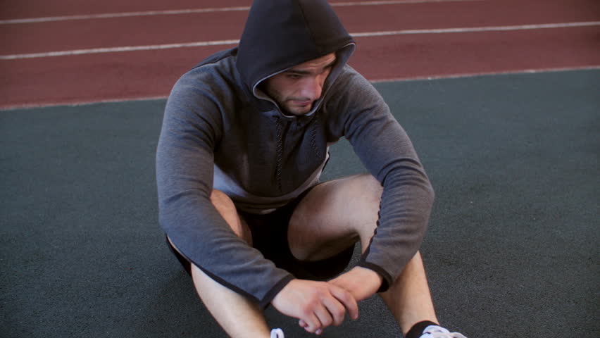 Athlete young man is sitting on floor and resting relax in gym wearing sportswear. He is deeply breathing. Tired exhausted sportsman. Workout training sport and active lifestyle concept. Male leisure. | Shutterstock HD Video #1100623045