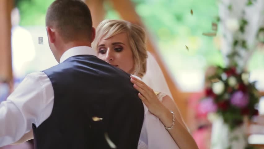 First dance of wedding pair in flying gold confetti. 