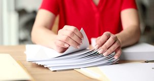 Hands of businesswoman look over stack of documents on office table